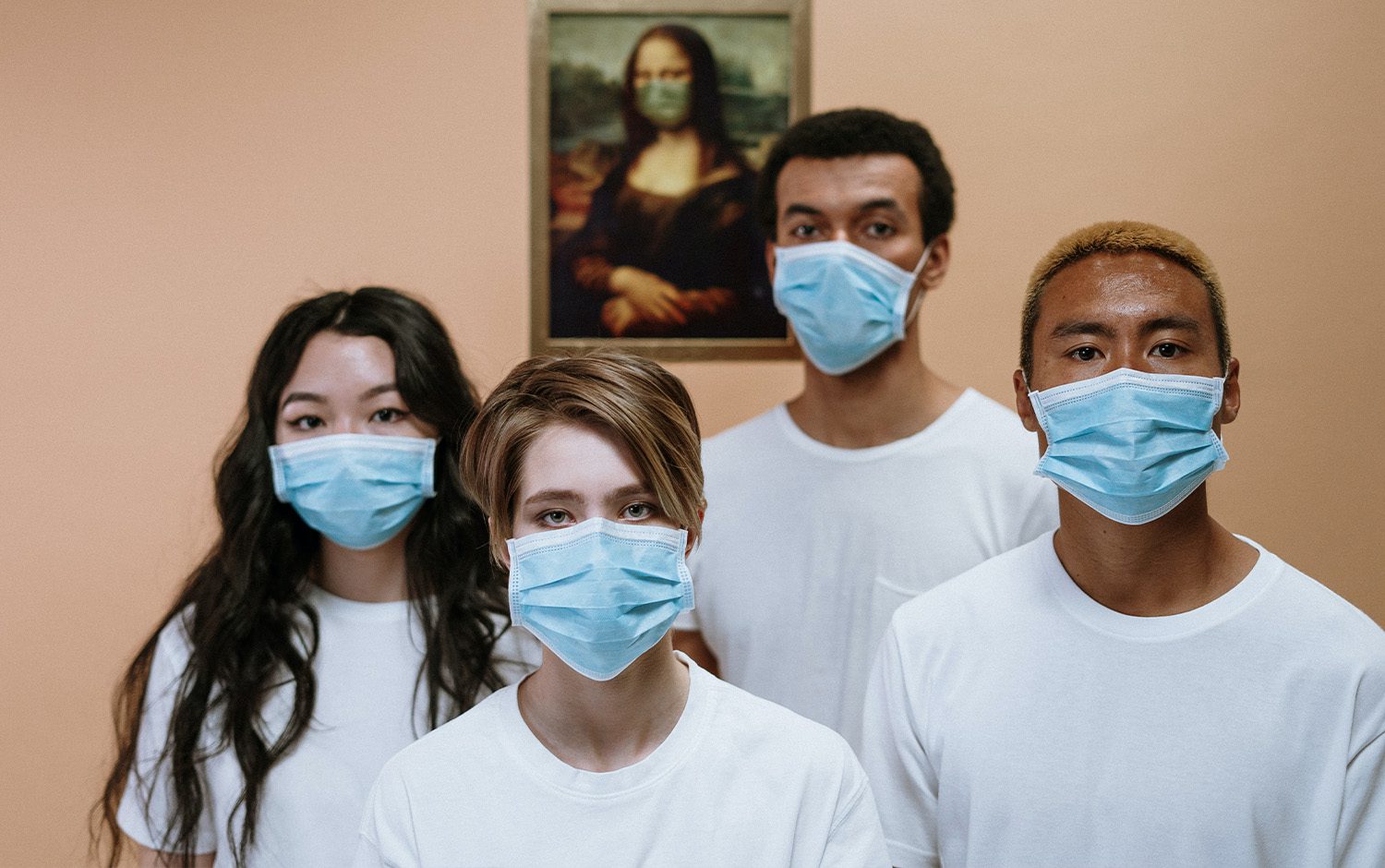 A group of people wearing surgical masks in front of a painting.