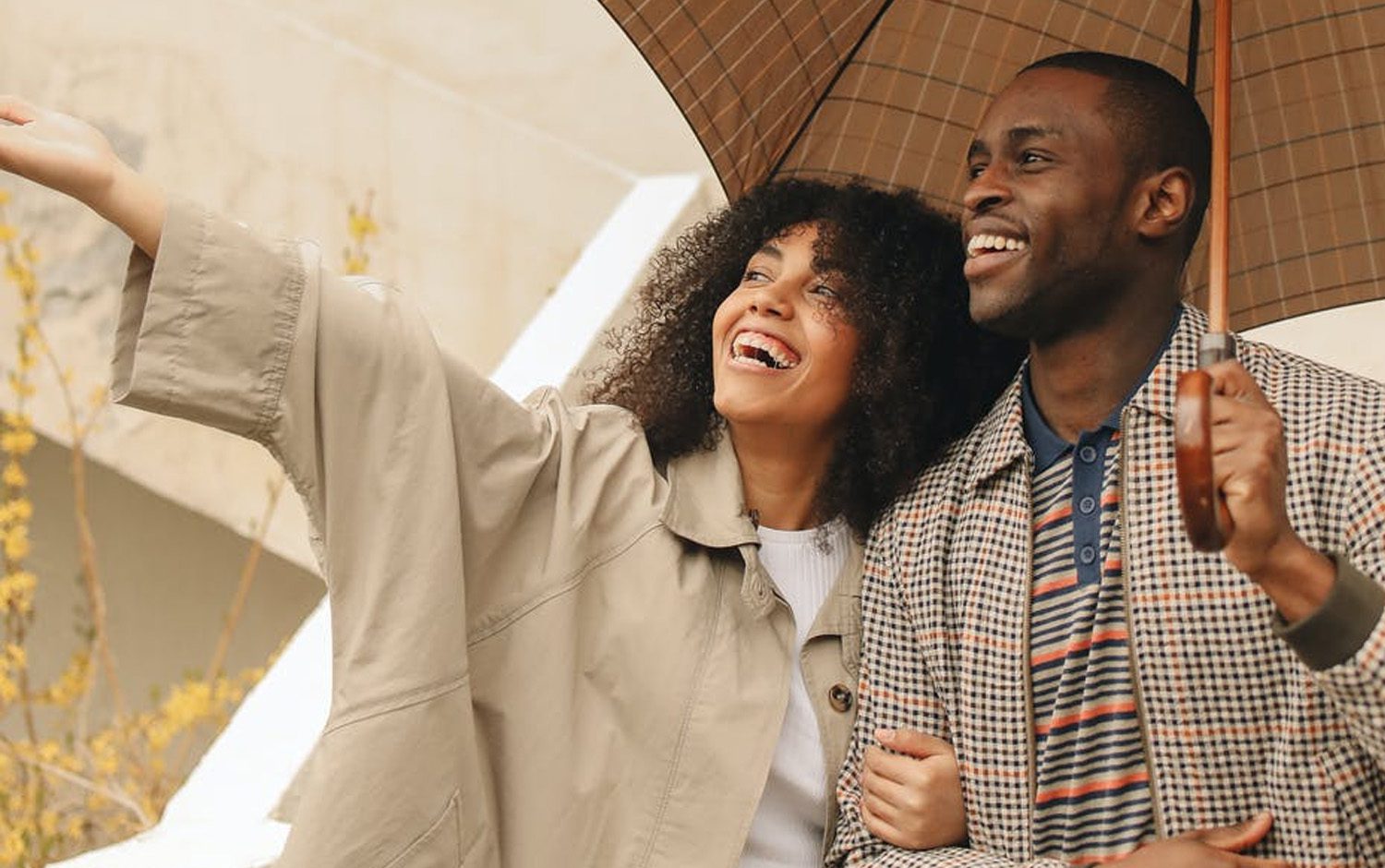 A couple holding an umbrella while smiling.