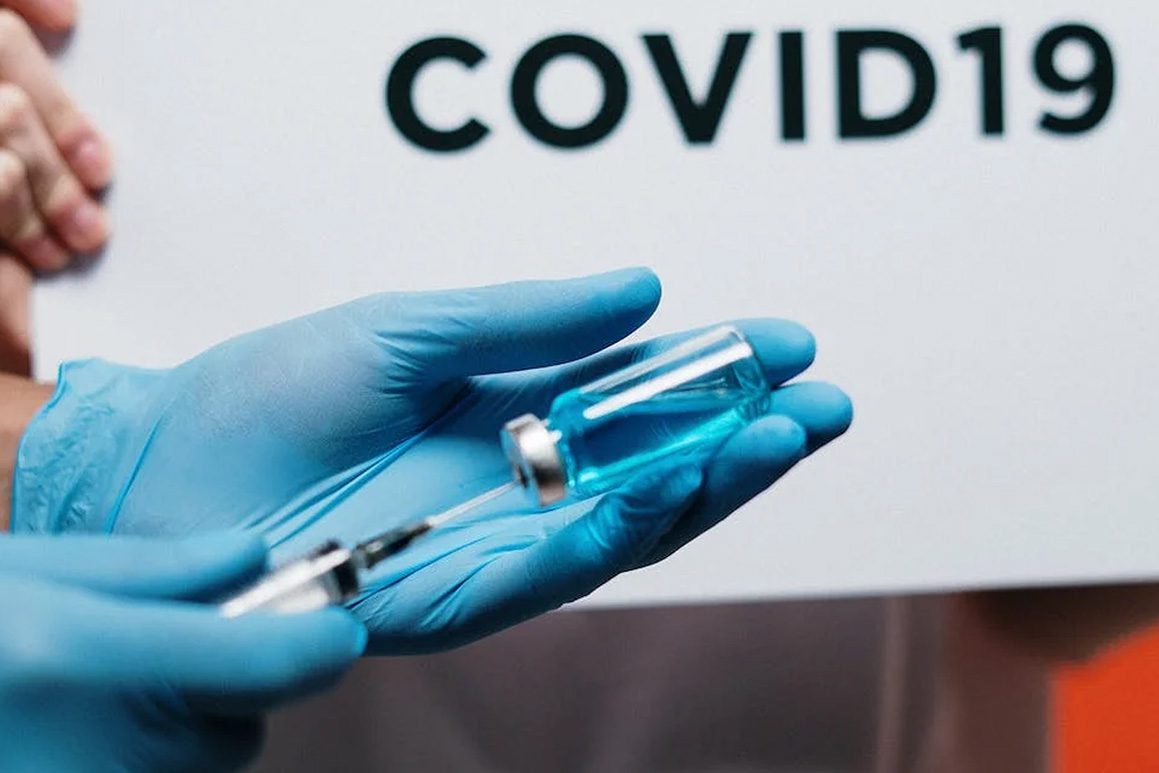 A person holding a syringe with the word covid19 on it.