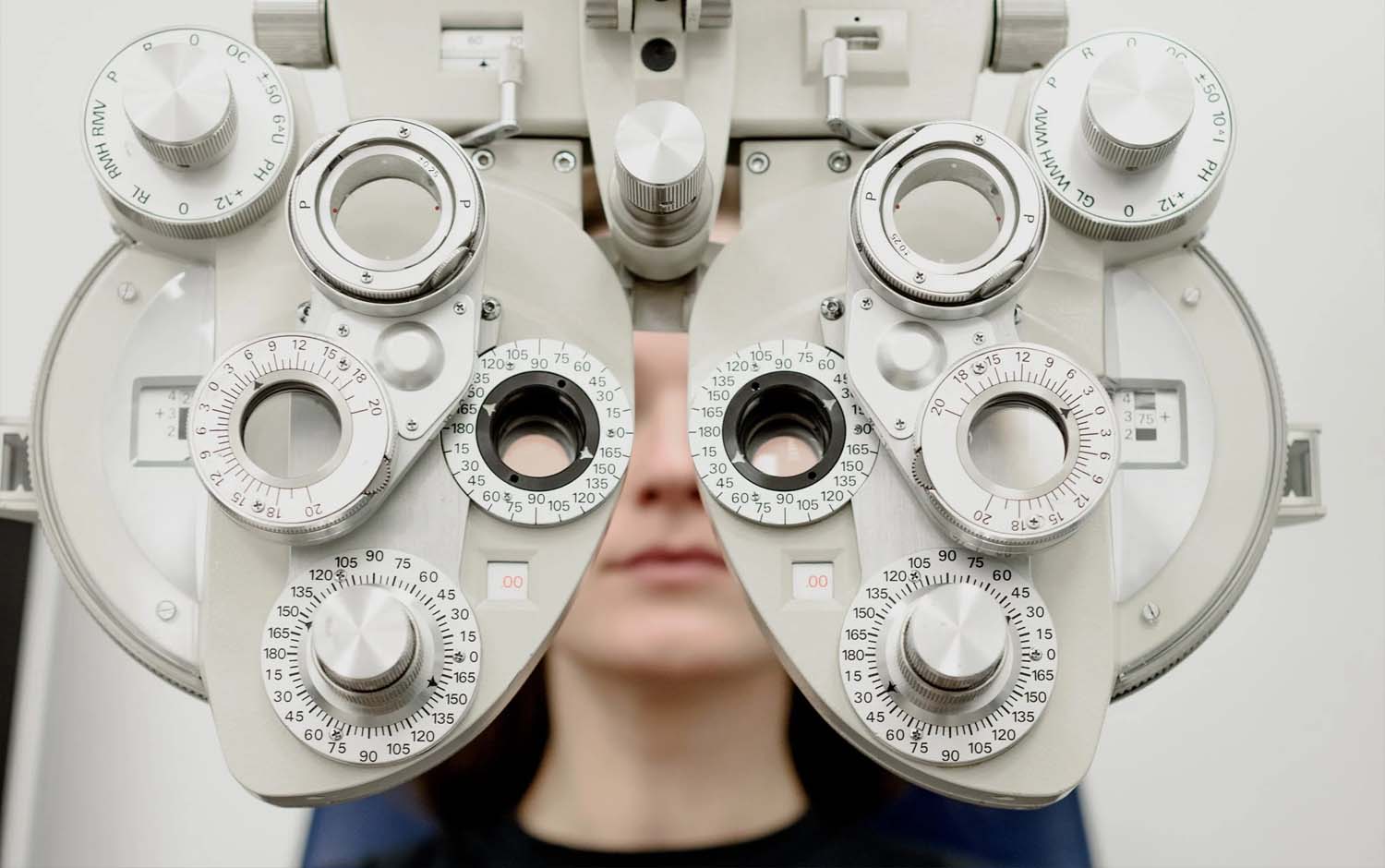 A woman is looking at an eye exam machine.