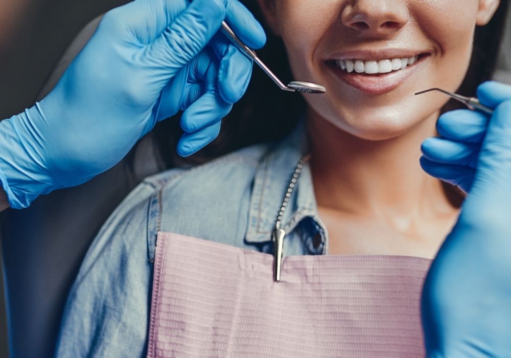 Dentist examining patient's teeth with tools.