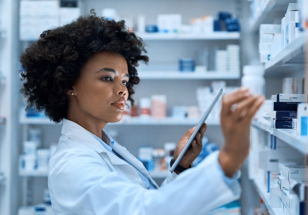 Pharmacist checking inventory on tablet.