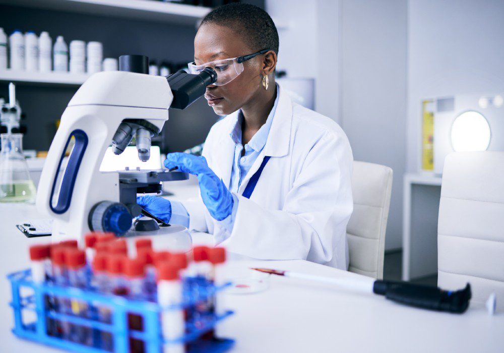 Science, laboratory and woman on microscope for blood test research, medical analysis and dna or virus tube.
