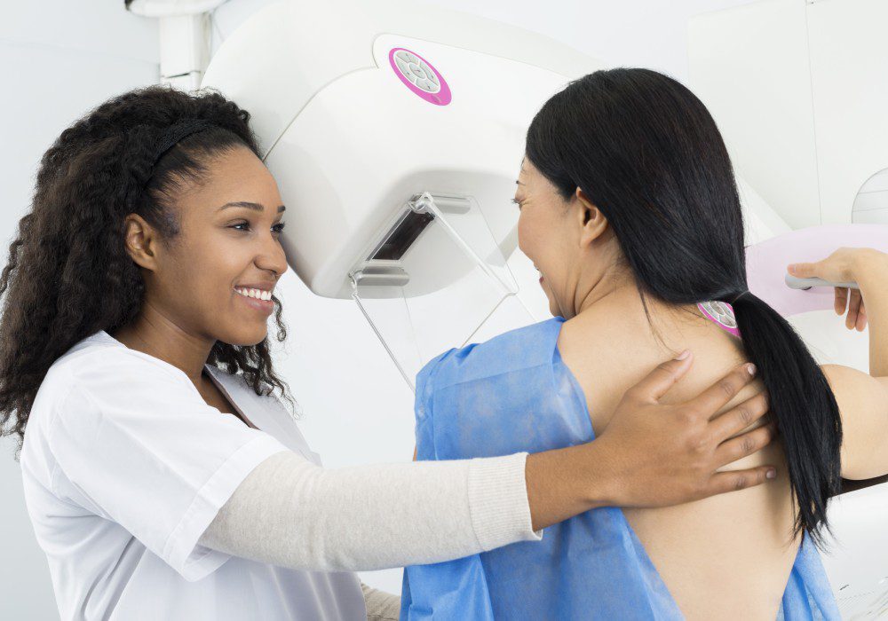 Smiling doctor helping woman during mammogram.