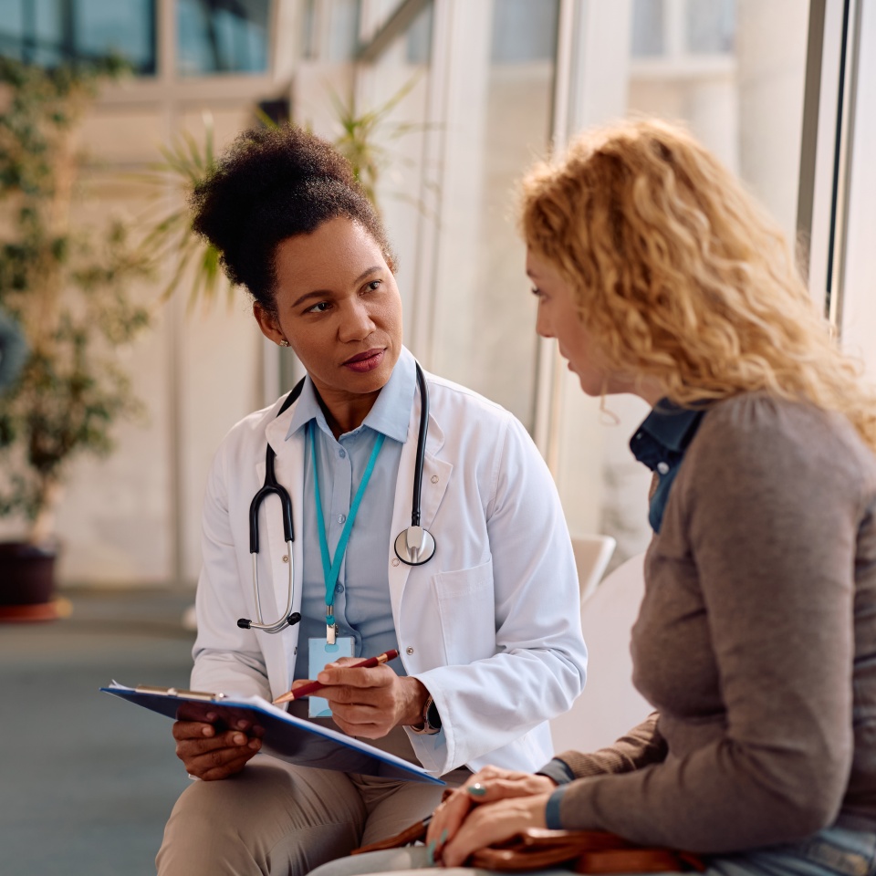 African American doctor and her female patient analyzing test results after medical examination at polyclinic.