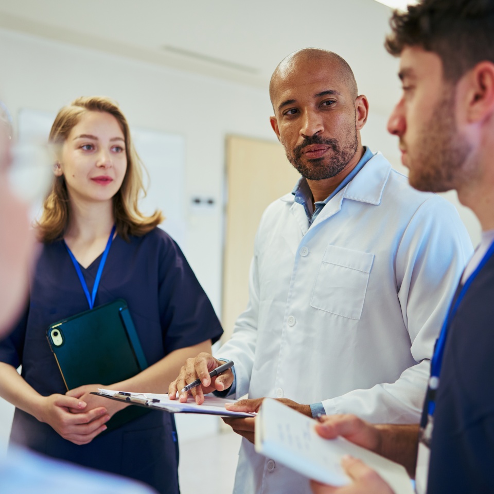 Doctors and nurses collaborating, reviewing medical records and strategizing patient care in a hospital hallway