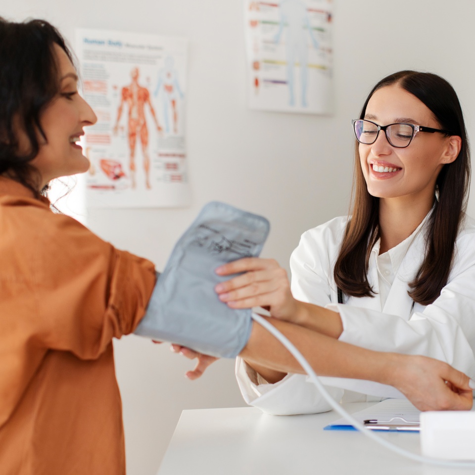 Professional woman doctor checking female patient with measure blood pressure in hospital. Concept of health checkup