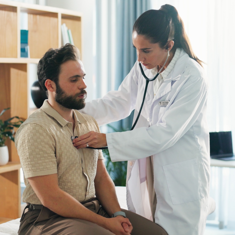 Hospital, listening and doctor with stethoscope for man for diagnosis, consulting and breath exam. Healthcare, clinic and patient with tools for cardiology, pulmonary service and medical checkup.