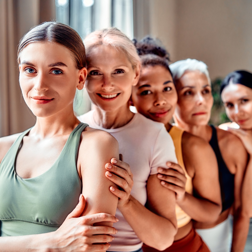 Diverse women of different ages smiling together in activewear, wellness and community concept.