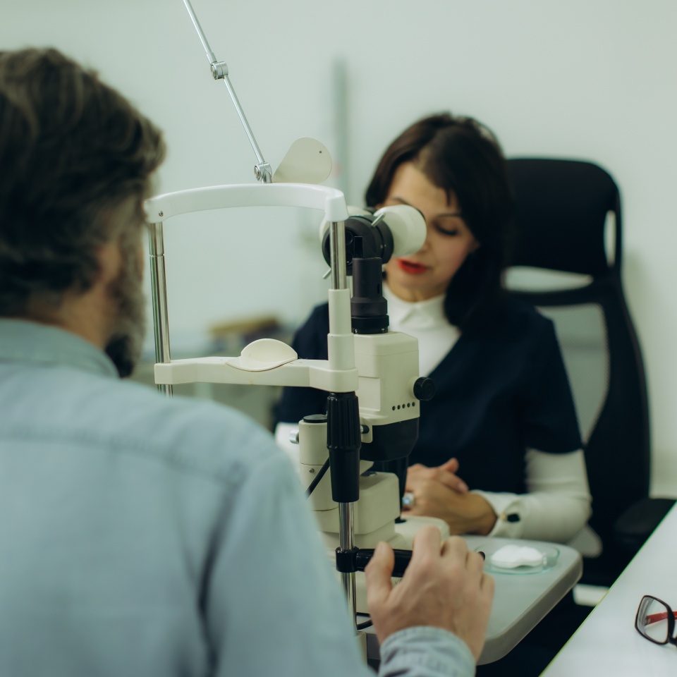 Ophthalmologist examining a patient's eye with a slit lamp microscope during a detailed vision check in a modern clinic
