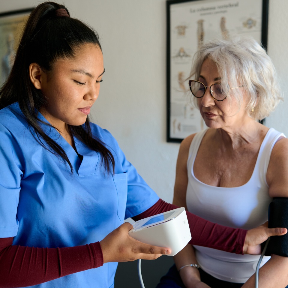 Nurse checking senior woman's blood pressure during a routine medical examination, promoting health, care, and well being