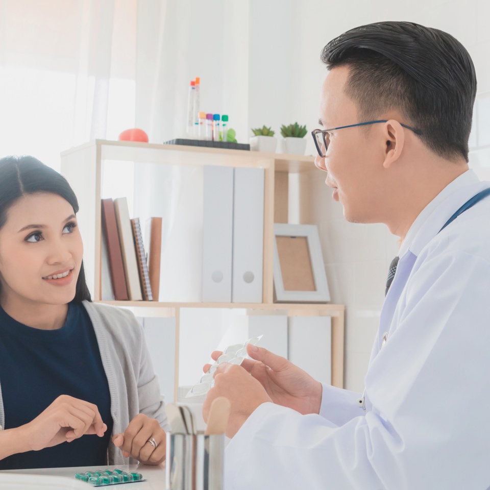 Professional doctor wearing white coat describe how to take medicine to woman patient in hospital background.Concept of disease treatment and health care in hospitals.