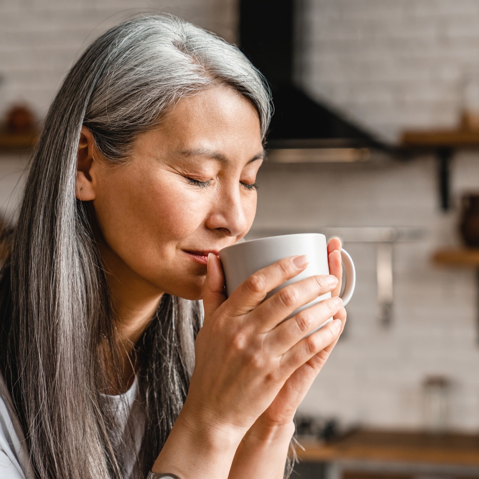 Nice-looking caucasian mature woman drinking hot coffee in the kitchen
