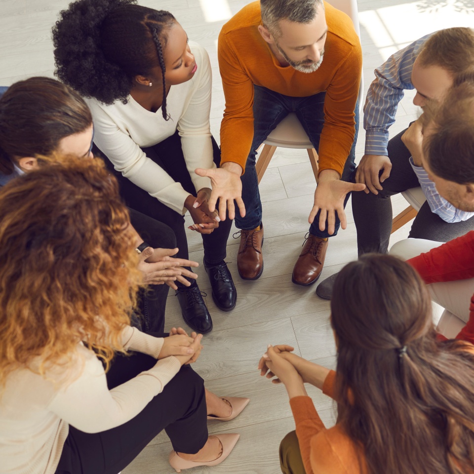 Professional therapist meeting with multiracial group therapy patients. Diverse people supporting each other and talking about their issues and ways to solve problems. View from above, high angle shot