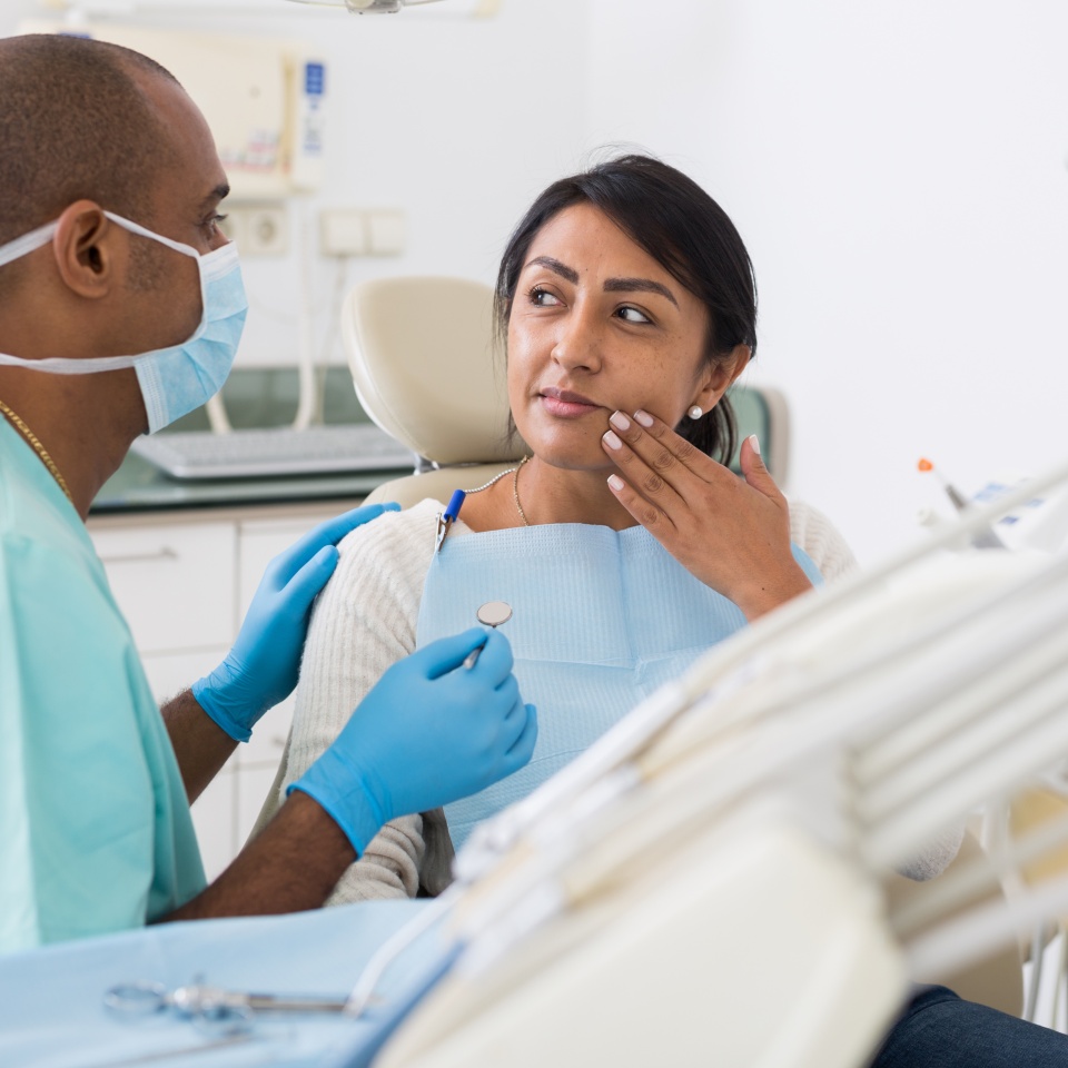 Woman patient talking to male dentist and complaining of toothache at dental clinic office