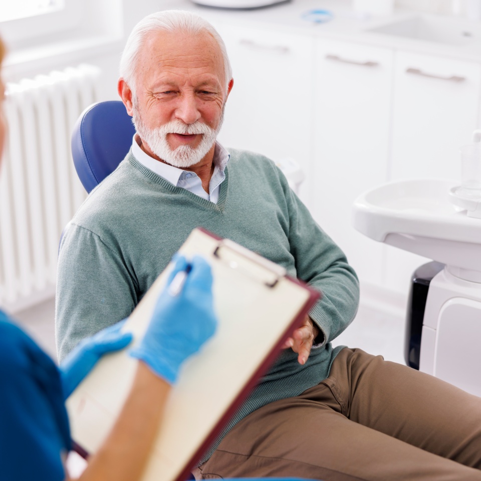 Senior man having dental checkup at dentist office, consulting with doctor about necessary procedures