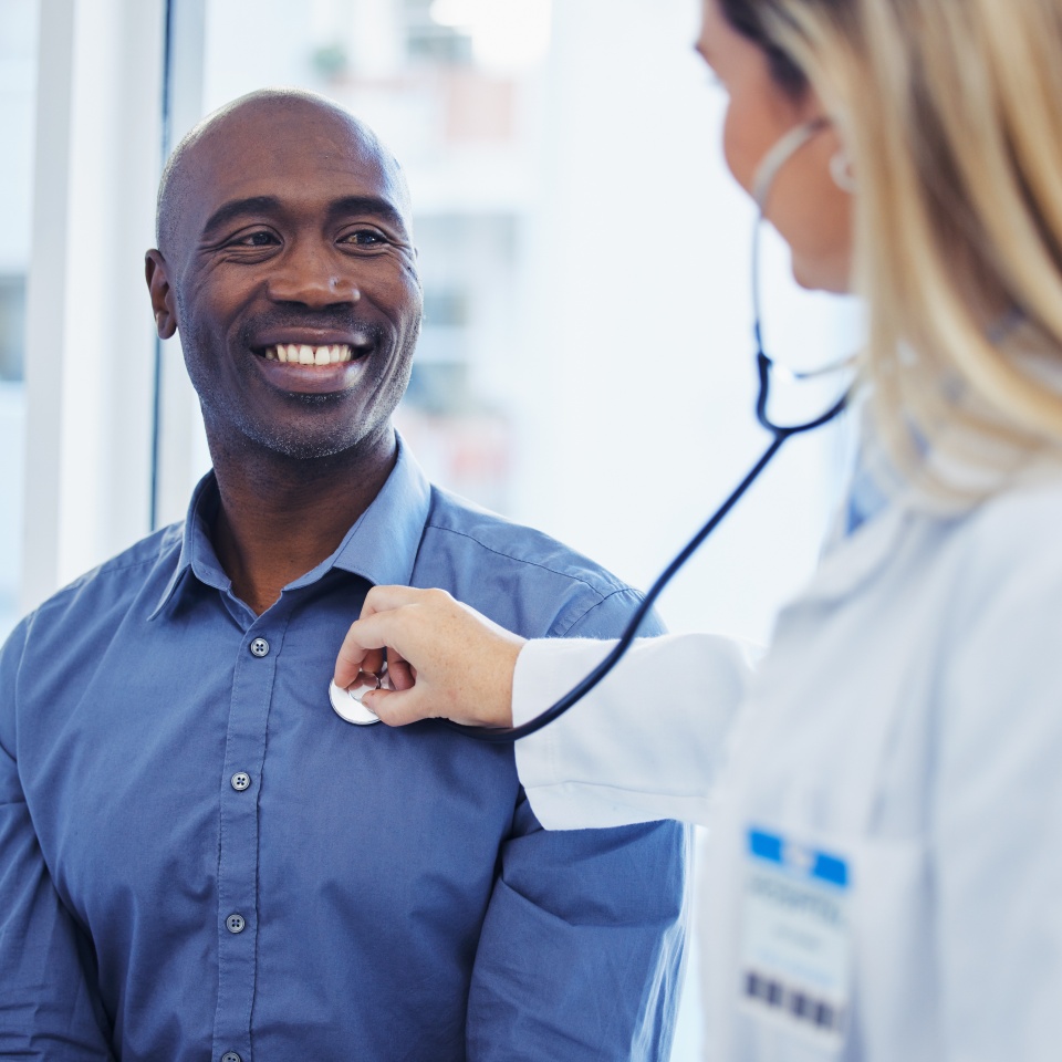 Patient, doctor woman and consultation with stethoscope in hospital for cardiology or health insurance. Black man and healthcare person talking about lungs, breathing and advice for healthy heart.