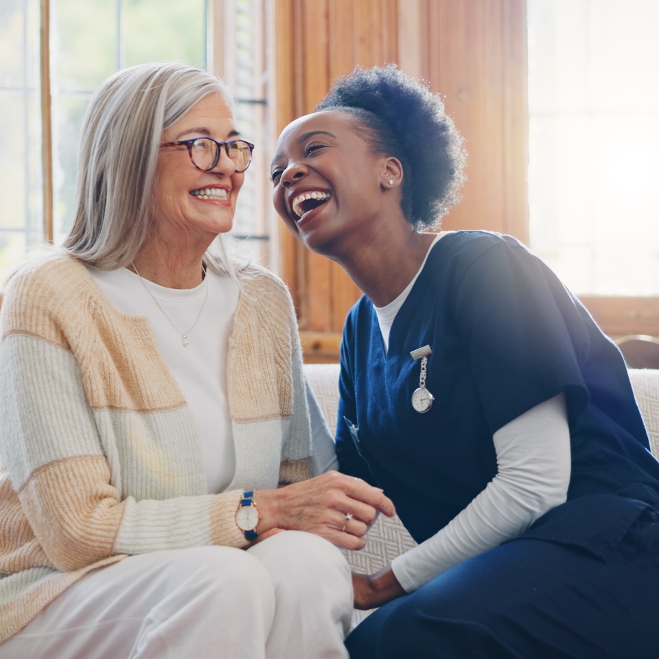 Senior patient, funny or happy caregiver talking for healthcare support at nursing home clinic. Smile, women laughing or nurse speaking of joke to a mature person or woman in a friendly conversation.