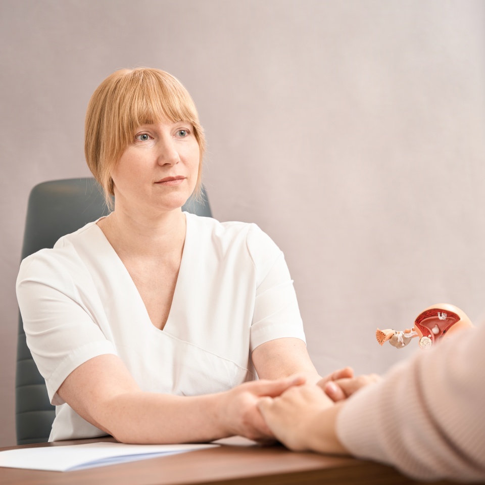 Caring female practitioner listening to patient story tightly holding her hands, supporting and empathising hearing news about miscarriage, healthcare and medicine