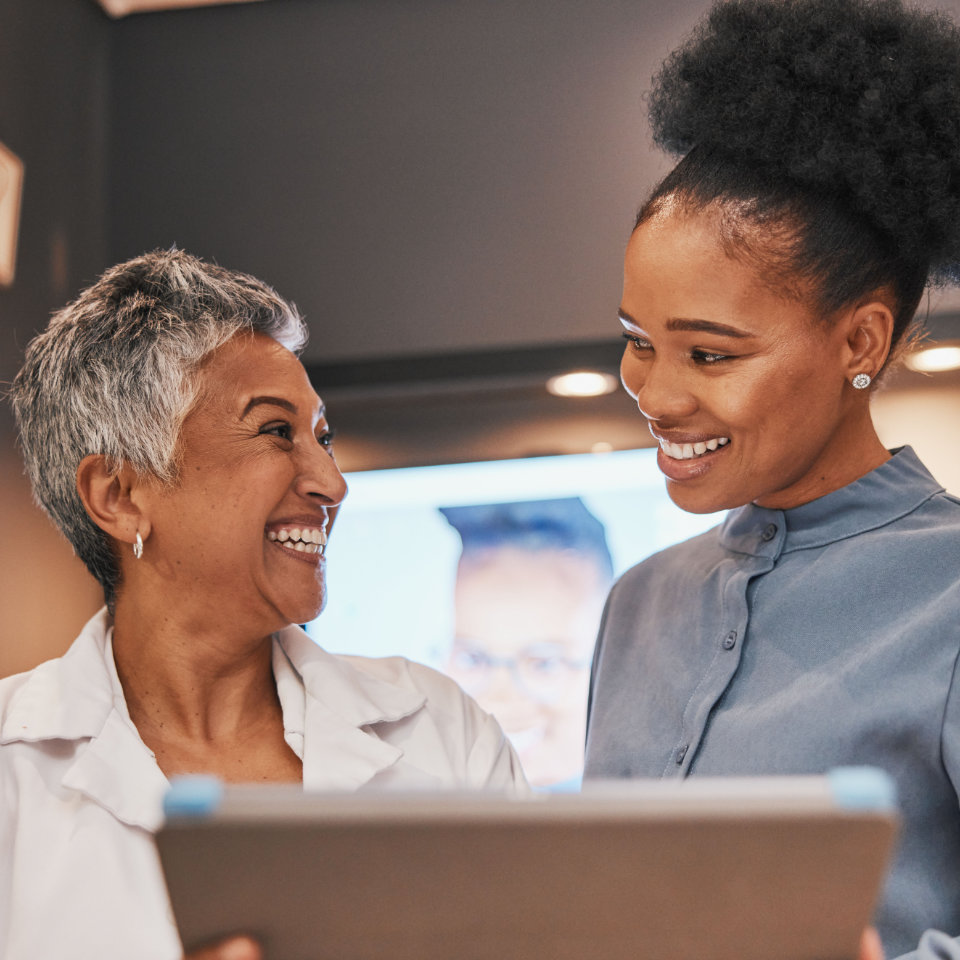 Optometry, tablet and optometrist talking to a patient about eye test results or consultation. Discussion, technology and senior optician speaking to a female with a mobile device at a optical clinic