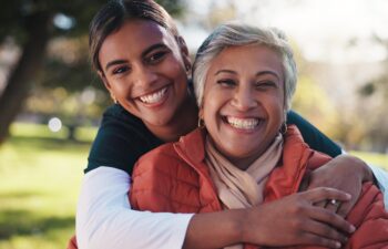 Hug, portrait and smile of caregiver with old woman in park for assisted living or rehabilitation. Love, support or wellness with happy nurse and senior patient embracing in nature for retirement