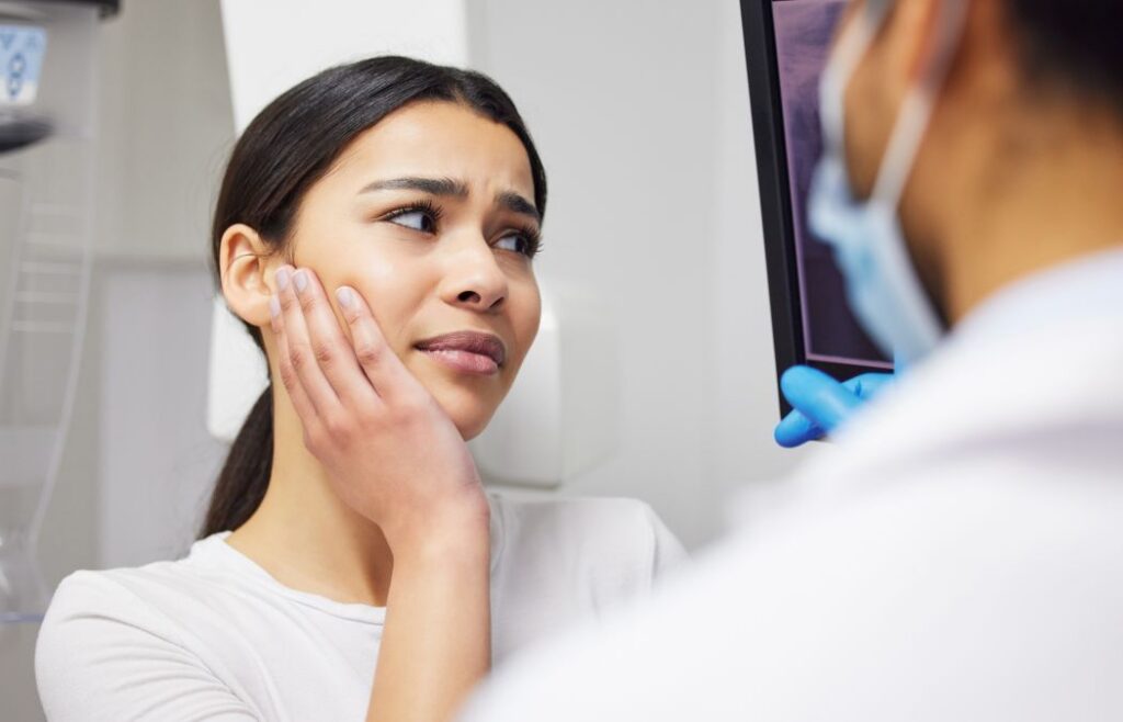 A woman with dental pain and a dentist revising the dental imaging