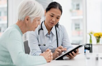 Results, tablet and senior woman with doctor talking about healthcare data, report or communication in elderly care or consultation. Patient, nurse and advice in meeting with medical worker or expert.