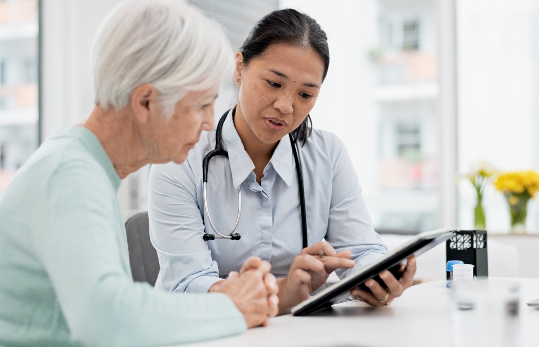 Results, tablet and senior woman with doctor talking about healthcare data, report or communication in elderly care or consultation. Patient, nurse and advice in meeting with medical worker or expert.