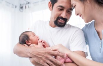smiling mother and father holding their newborn baby at home. portrait of happy family at home, young parents holding on hands little sweet newborn baby, love and happiness concept.