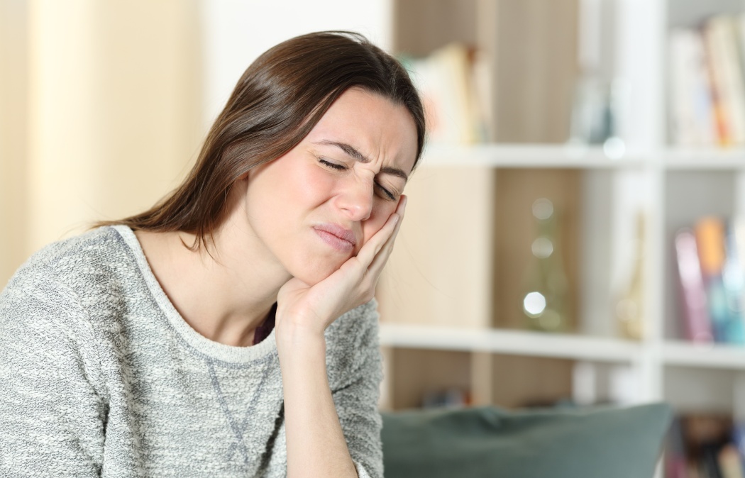Stressed woman suffering toothache complaining touching cheek on a couch at home