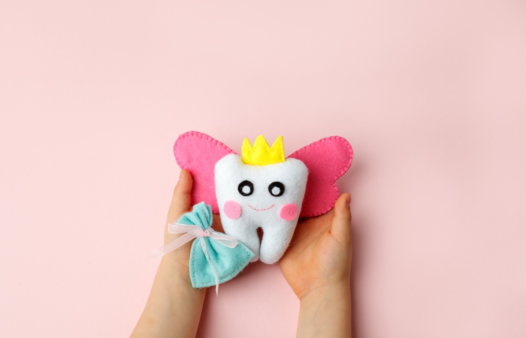 Little child holding felt tooth fairy toy in his hands on pink background. Easy and funny kids crafts, DIY, Happy Tooth Fairy greeting card, flyer, copy space, concept of tooth changes